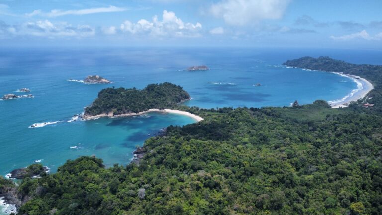 Aerial view of Manuel Antonio National Park in Costa Rica, featuring tropical rainforest, turquoise waters, and secluded beaches along the Pacific coast.