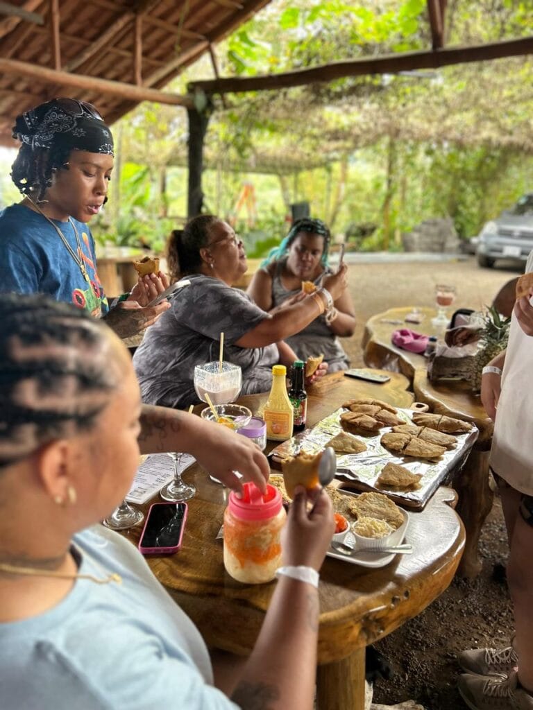 Open-air dining setup at a mountain restaurant near Jaco, Costa Rica, featuring a round wooden table with panoramic views of green hills and blue skies.