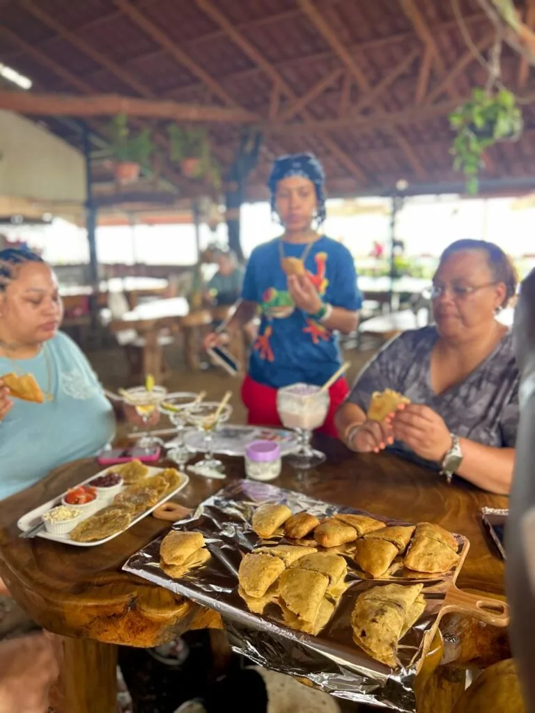 Group of women enjoying handmade empanadas and traditional Costa Rican dishes at Doña Marta’s mountain restaurant, with a wooden table full of food and drinks in an open-air dining space.