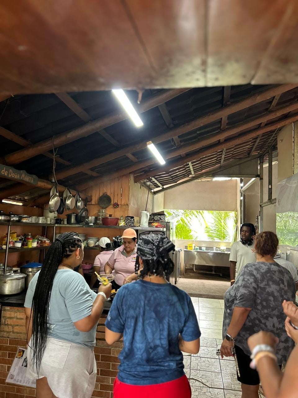 Guests gather inside the rustic kitchen at Doña Marta’s restaurant near Jaco, Costa Rica, as part of an interactive culinary tour experience. Pots, dishes, and ingredients fill the background.