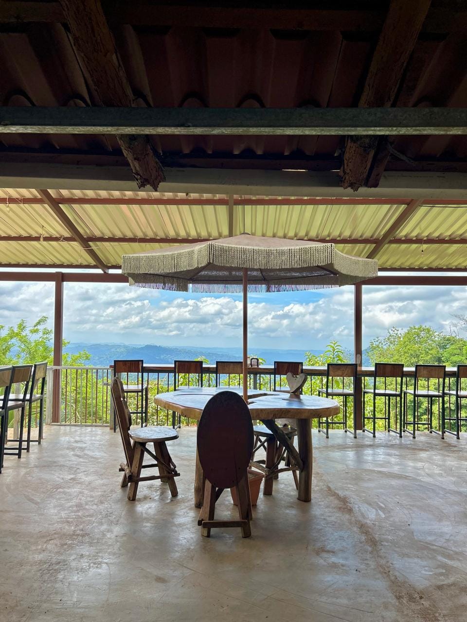 Open-air dining area at Doña Marta’s restaurant near Jaco, Costa Rica, with a round wooden table and chairs overlooking lush mountain views under a covered patio.