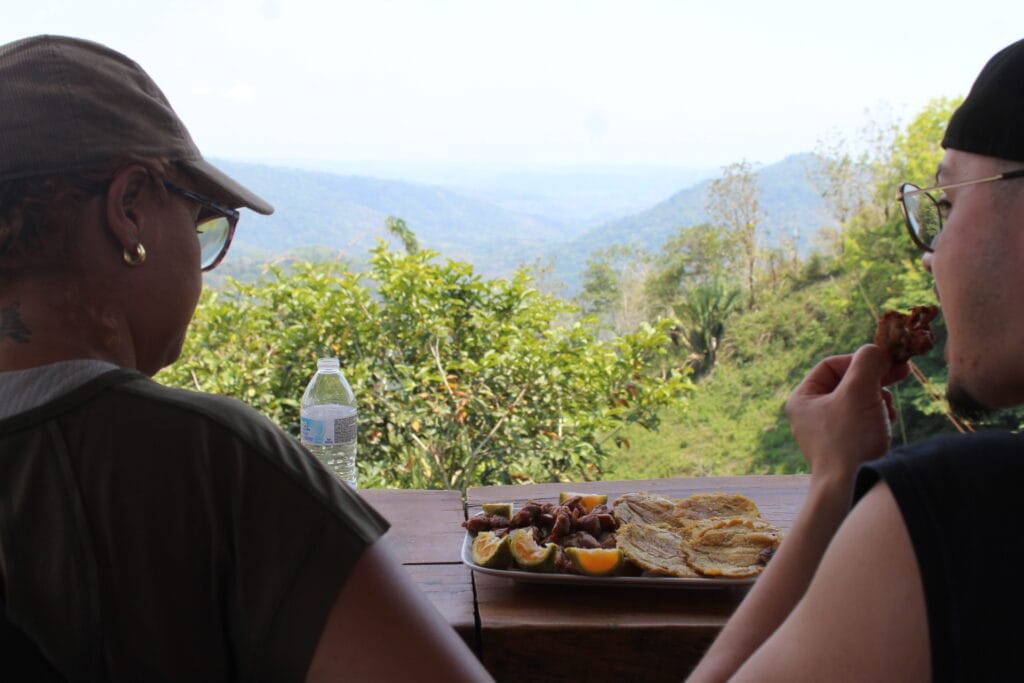 Guests enjoying a traditional Costa Rican meal with plantains and meat while overlooking mountain views near Jaco, Costa Rica.