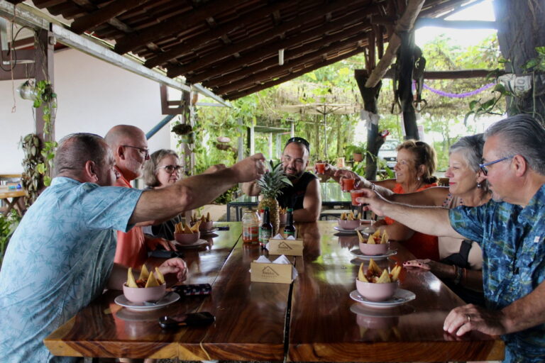 Group of travelers toasting over traditional Costa Rican snacks at an open-air local restaurant