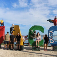 Group of travelers posing at the Jaco Costa Rica sign before their adventure