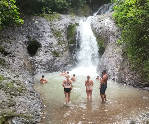 Group of travelers swimming and relaxing at a scenic jungle waterfall in Costa Rica — part of an adventure tour near Jacó