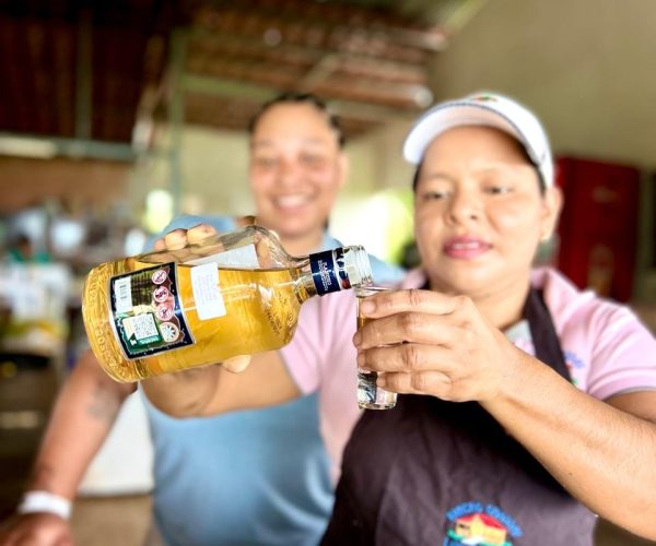A smiling staff member at Doña Marta’s mountain restaurant near Jaco pours a shot of local liquor for a guest, adding a fun and authentic touch to the culinary experience.